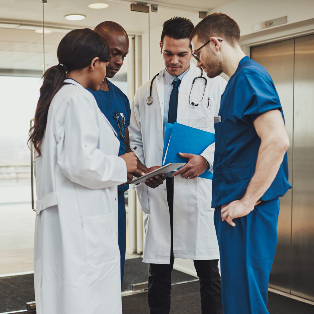 Medical team consulting on a patient records standing in a foyer at a hospital grouped around a tablet computer